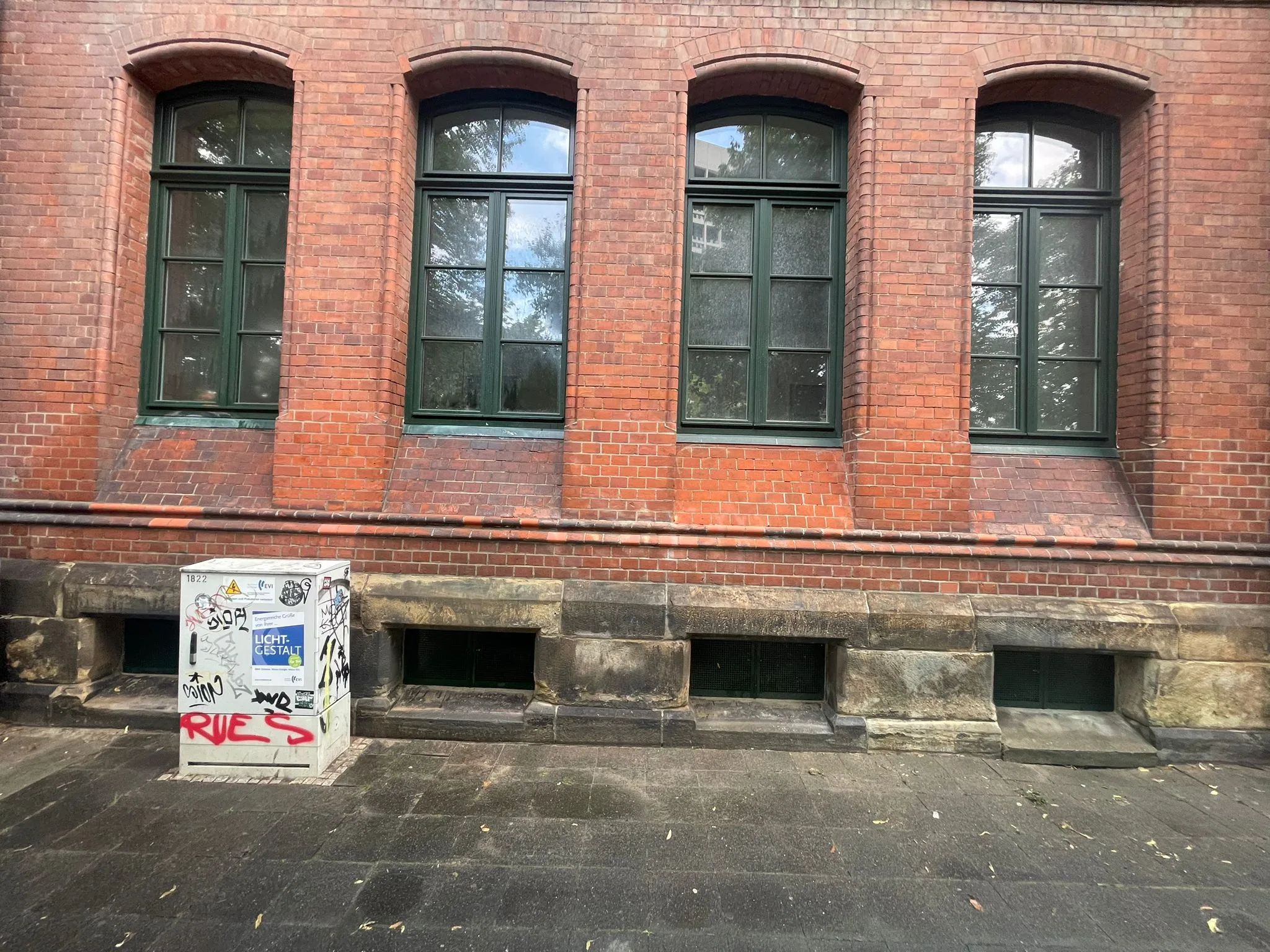 Ściana budynku z widocznymi oknami oraz graffiti na niższej części elewacji