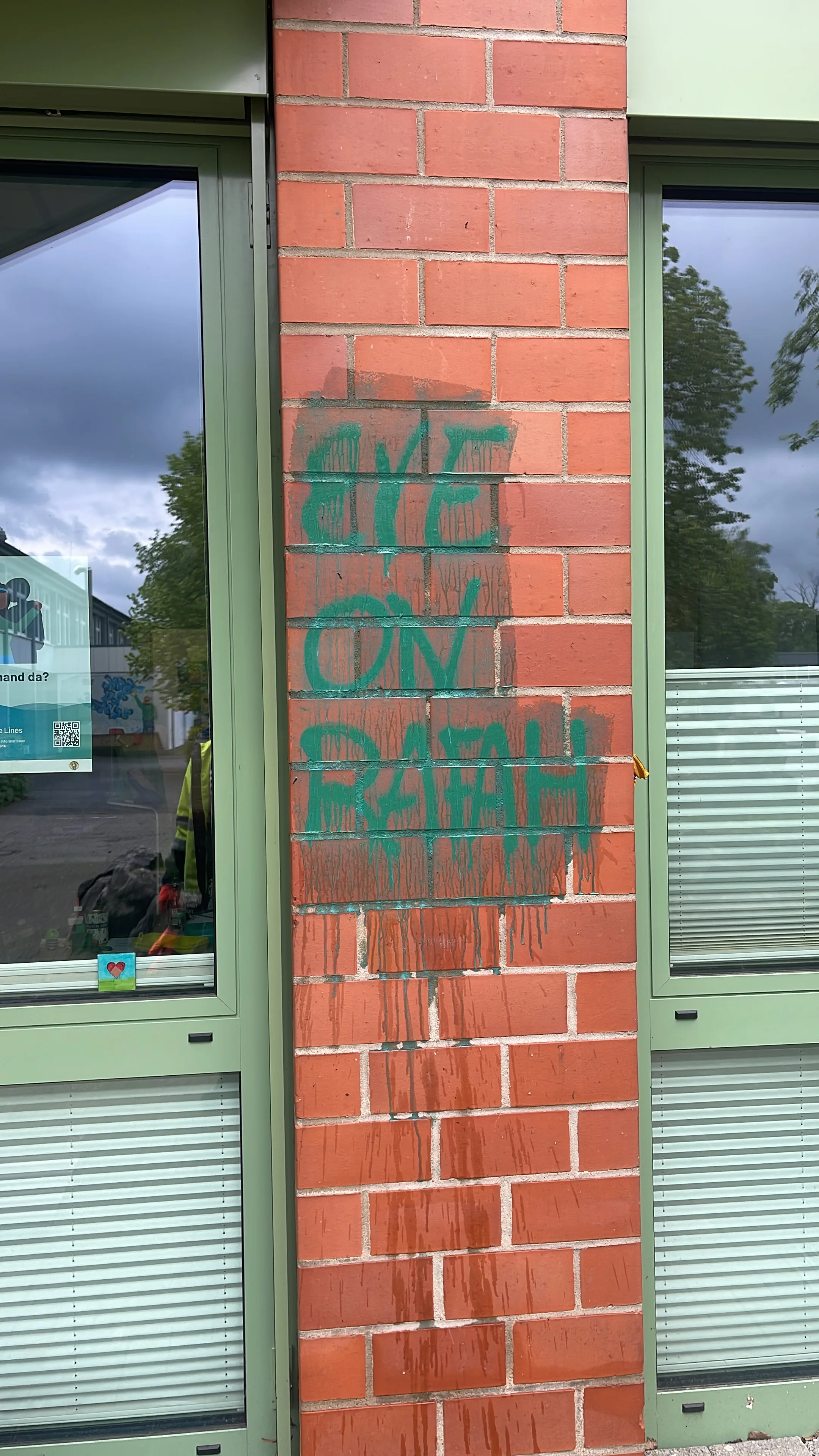 Zabrudzona elewacja z graffiti w zielonym kolorze, podnawana do czyszczenia